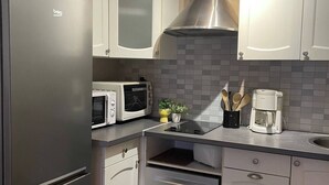 A modern kitchen with a stainless steel refrigerator, a microwave, a coffee maker, and a built-in oven. - Le rétro du Marché (La Rochelle)