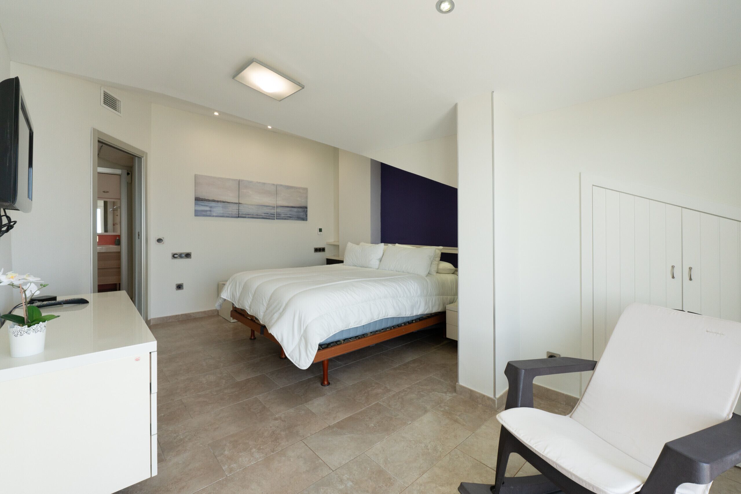 A modern bedroom with a bed, a desk, and a chair.