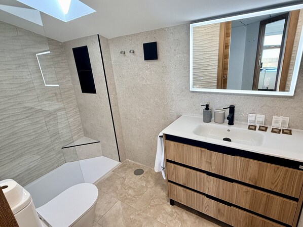 Une salle de bain moderne équipée d’une douche, de toilettes et d’un meuble-lavabo.