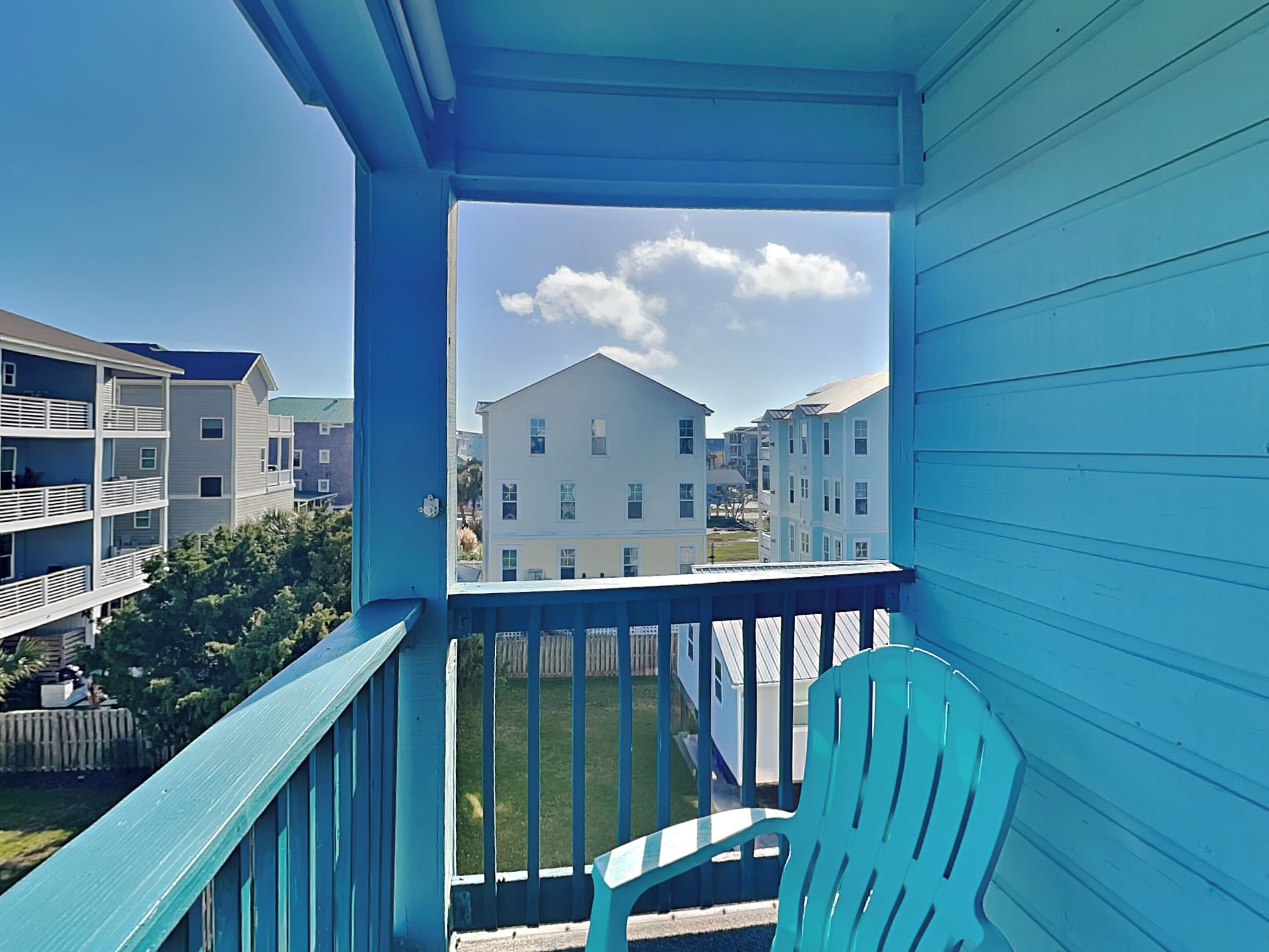 A balcony with a view of neighboring buildings and a clear sky.