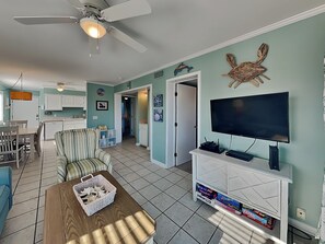 Un salon équipé d’un téléviseur, d’un ventilateur de plafond et d’un coin repas avec des chaises et une table.