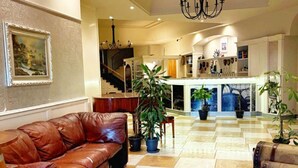 A spacious lobby with a checkered floor, leather sofas, a chandelier, and a staircase leading to upper floors. - HOTEL BUSINESS (Casoria)