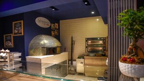 A kitchen area with a pizza oven, a display case with food items, and a sign that reads "La Tradizza." - HOTEL BUSINESS (Casoria)