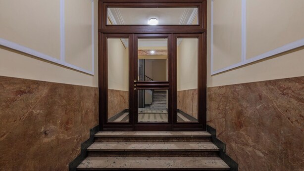 A staircase with marble steps and a red carpet leading to a door with a glass panel. - Old Soul New Comfort by Wonderful Italy (Turin)