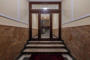 A staircase with marble steps and a red carpet leading to a door with a glass panel. - Old Soul New Comfort by Wonderful Italy (Turin)