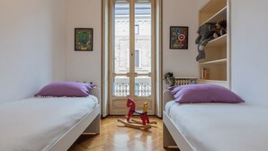 A room with two beds, a wooden rocking horse, and a window with a view of buildings. - Old Soul New Comfort by Wonderful Italy (Turin)
