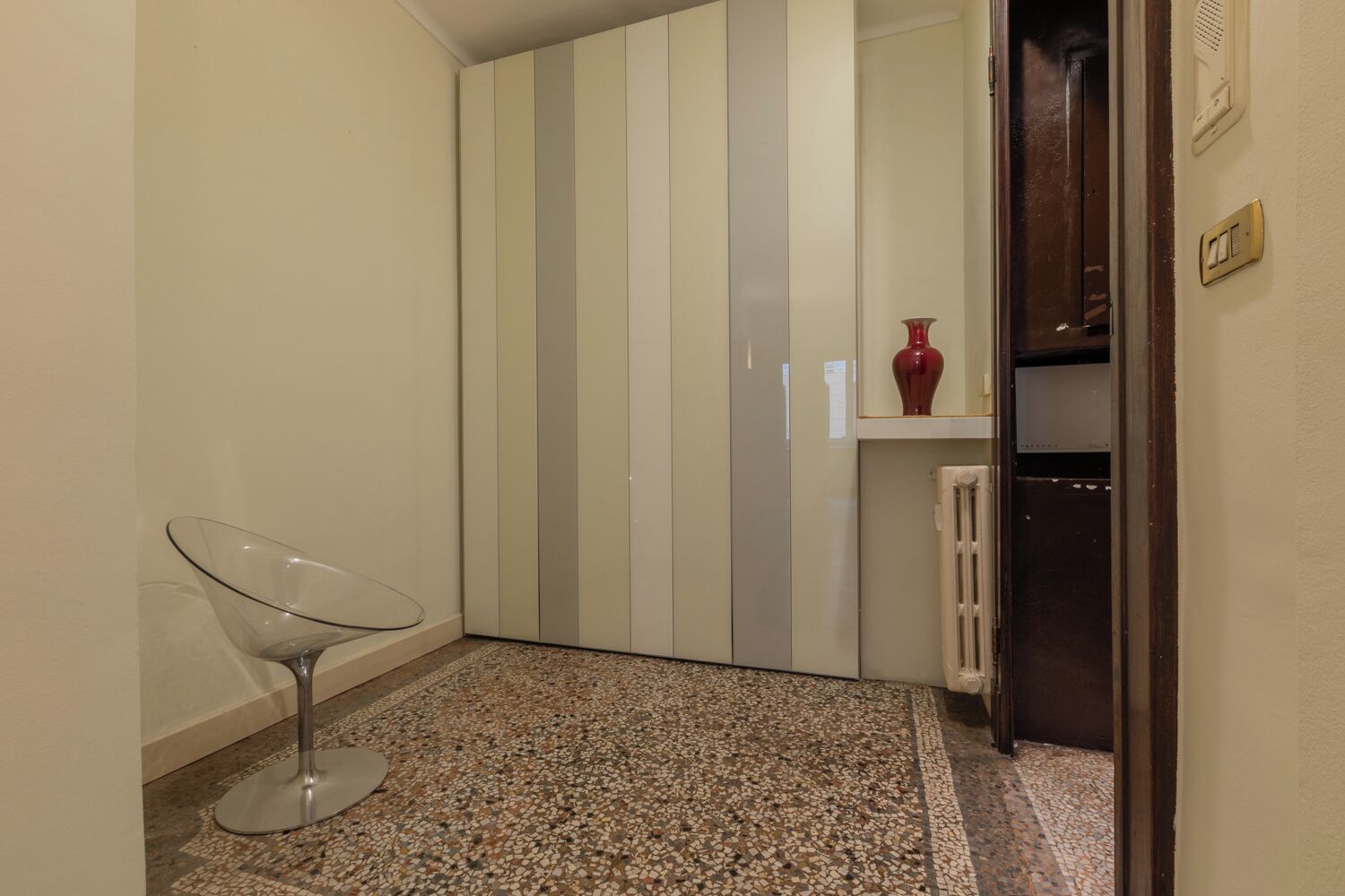 A room with a striped wardrobe, a glass table, and a radiator.