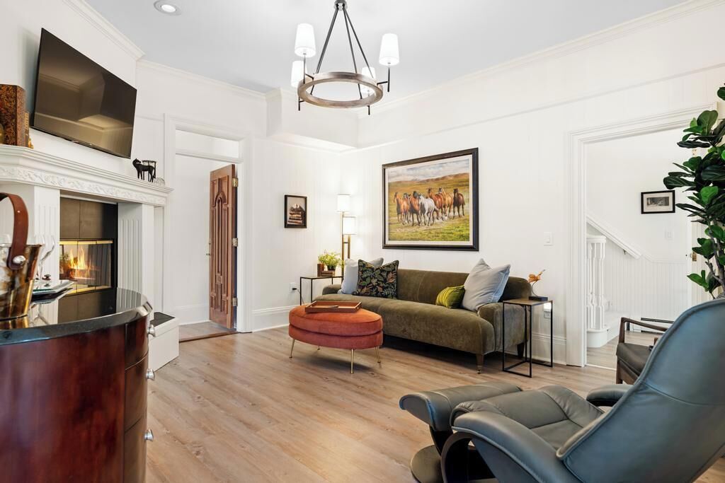 Una sala de estar con chimenea, un sofá, una mesa de centro y un televisor sobre la chimenea.