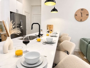 A modern kitchen with a white countertop, black faucet, and a wooden clock on the wall. - Sleeps 25 - Karaoke, Dome, Hot Tub, Games, Makeup Station & Rooftop Soccer (Dallas)