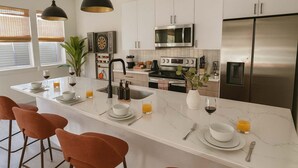 Una cucina moderna con isola centrale, elettrodomestici in acciaio inossidabile e illuminazione a sospensione.