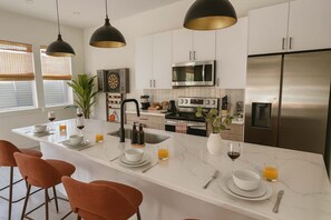 A modern kitchen with a central island, stainless steel appliances, and pendant lighting.