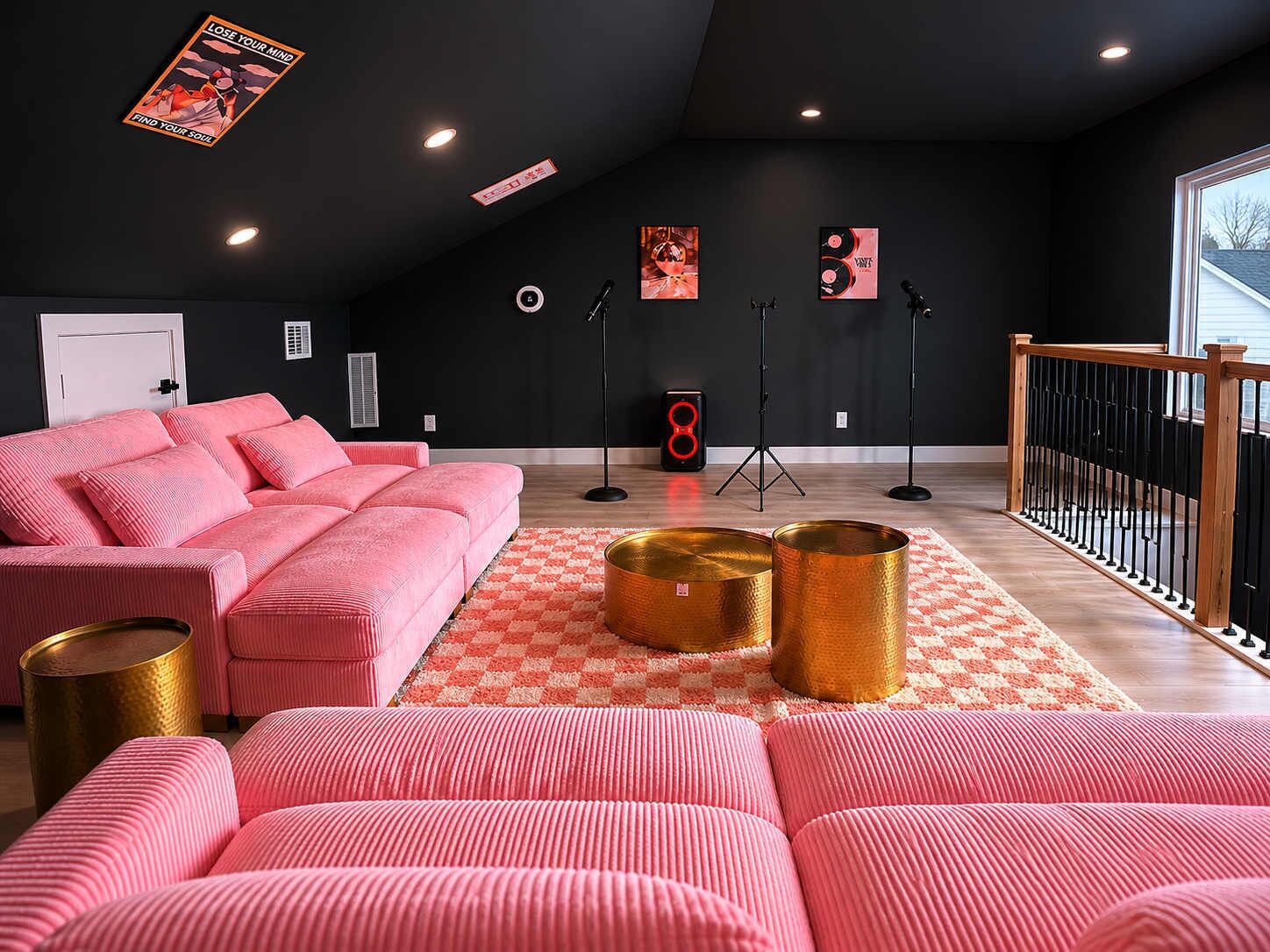 Un salon moderne avec un canapé rose, un tapis à carreaux et un escalier doté d’une rampe en bois.