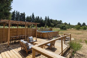 Een houten terras met buitenmeubilair, een jacuzzi en een pergola.