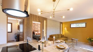 A modern kitchen with an induction cooktop, a dining area with a round table, and a living room with a sofa and a window. - Mas9Romanin:Gîte Evasion in Provence (Saint-Rémy-de-Provence)