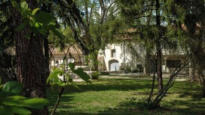 A courtyard with a building featuring an arched entrance and a stone pathway. - Mas9Romanin:Gîte Evasion in Provence (Saint-Rémy-de-Provence)
