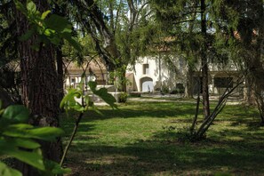 A courtyard with a building featuring an arched entrance and a stone pathway. - Mas9Romanin:Gîte Evasion in Provence (Saint-Rémy-de-Provence)