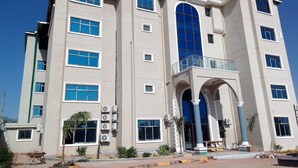 A multi-story building with a central entrance, large windows, and a balcony on the upper floor.