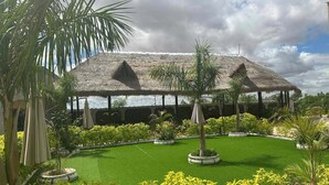 A resort with thatched-roof structures, a well-maintained lawn, and tropical landscaping.
