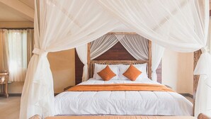 A bed with a canopy and two pillows, a wooden headboard, and a window with curtains.