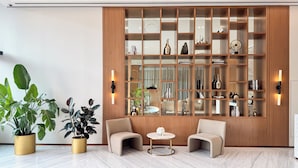 A modern room with a wooden cabinet, two armchairs, a small round table, and potted plants. - PVH - Cozy 1BR - Binghatti House (Dubai)