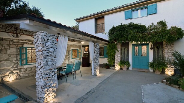 A stone building with a covered patio, a door with a metal gate, and a clock. - Villa Buby by Villas Guide (Kraljevica)