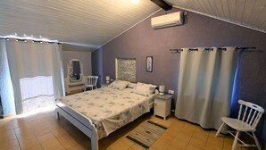 A bedroom with a bed, a chair, a nightstand, an air conditioning unit, and a window with curtains. - Villa Buby by Villas Guide (Kraljevica)