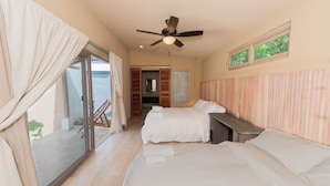 A hotel room with a large bed, a smaller bed, a desk, and a ceiling fan. - Casa Nära Hotel (San Juan del Sur)
