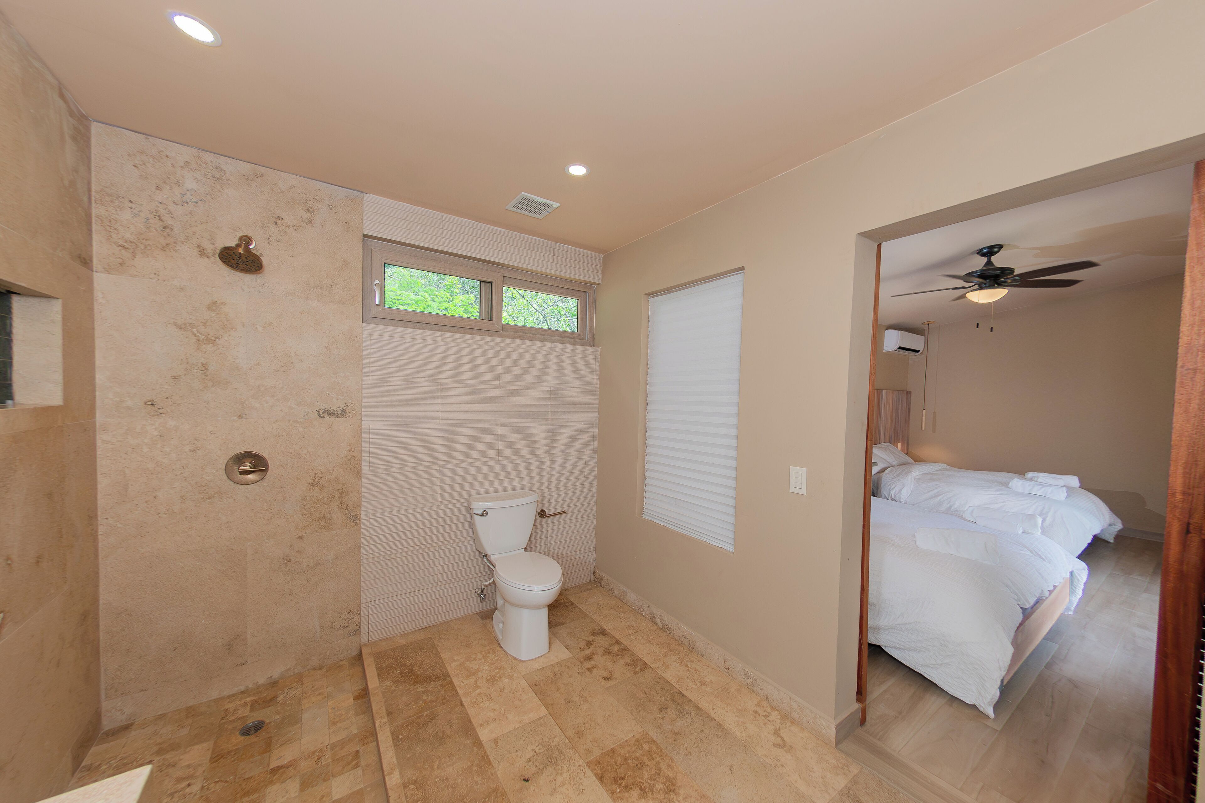 Un bagno con doccia e servizi igienici, e un letto nella stanza comunicante.