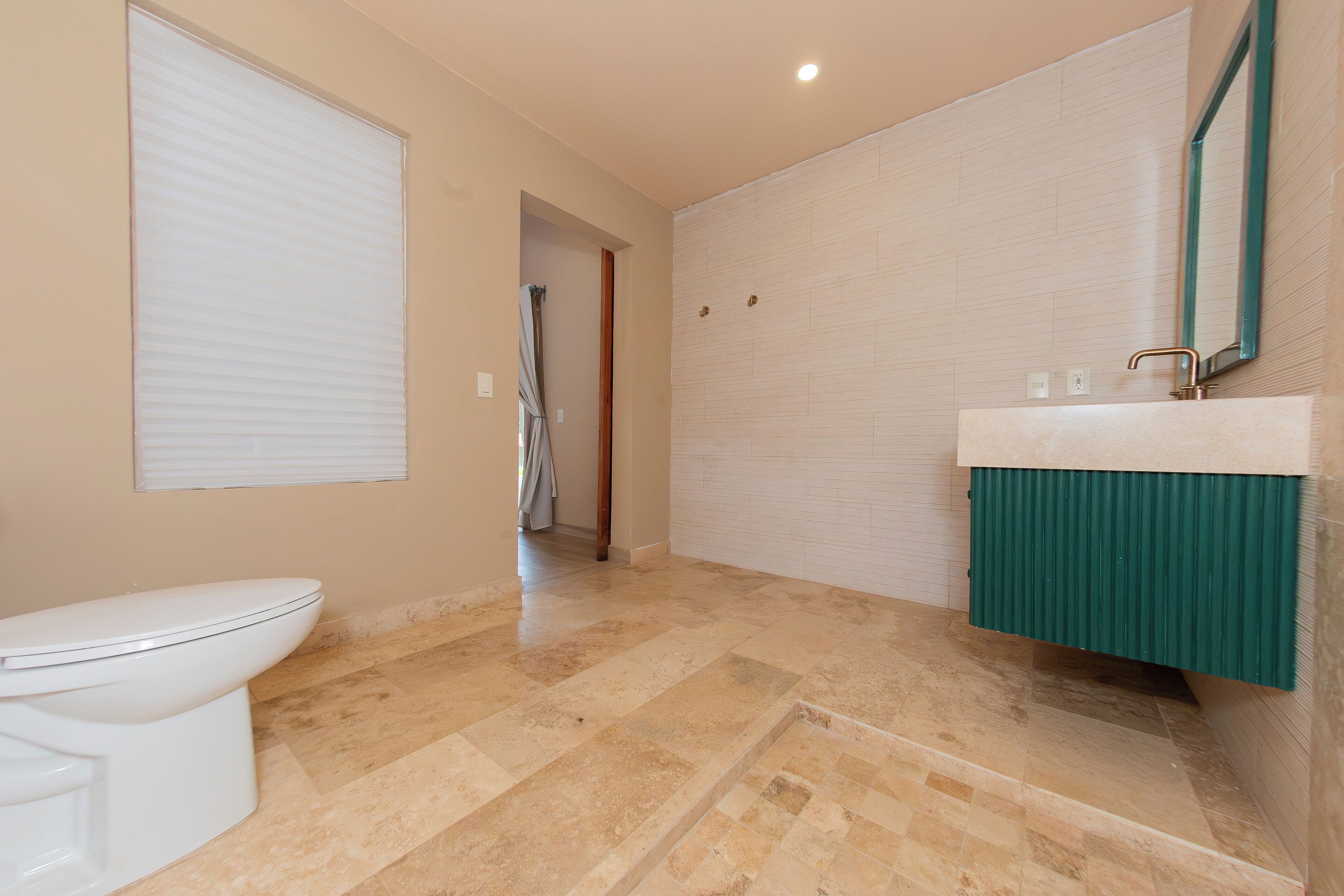 A bathroom with a toilet, a sink with a green cabinet, and a shower area.