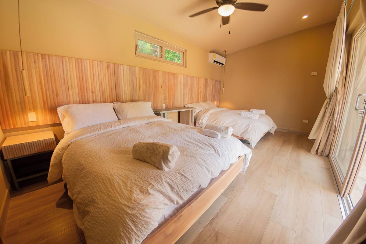 Une chambre d’hôtel avec un grand lit, une petite table et un ventilateur de plafond.