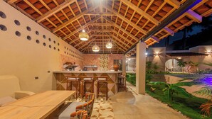 An outdoor dining area with a wooden ceiling, bar stools, and a patterned floor. - Casa Nära Hotel (San Juan del Sur)