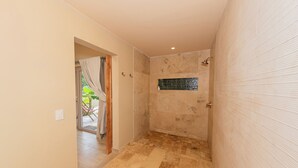 A bathroom with a shower, tiled floor, and a window with a view of greenery. - Casa Nära Hotel (San Juan del Sur)