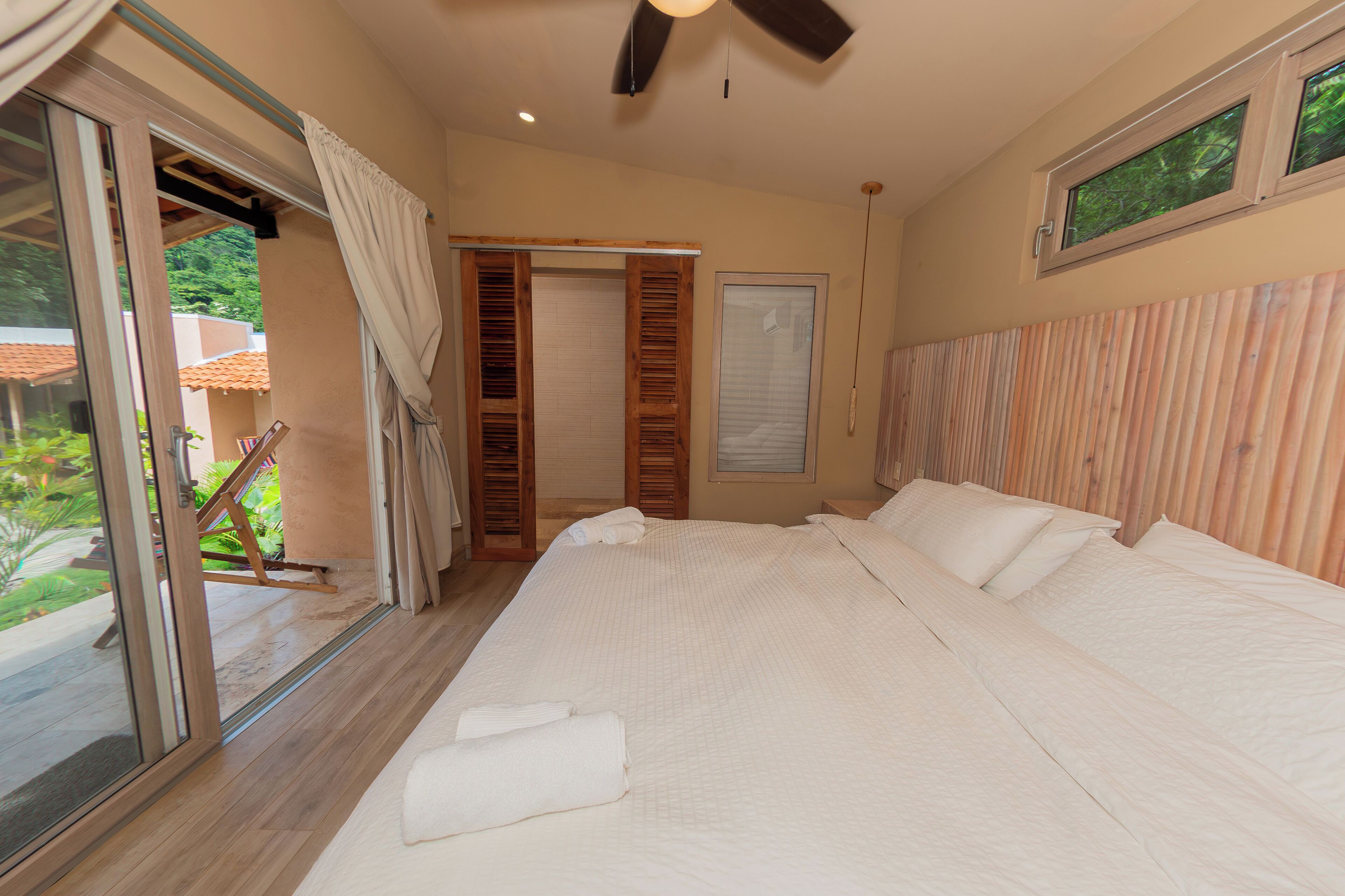 Amplia habitación con cama, puerta corrediza de vidrio y vista al exterior.