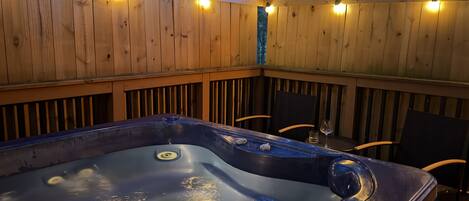 Un jacuzzi con terraza de madera y luces cálidas.