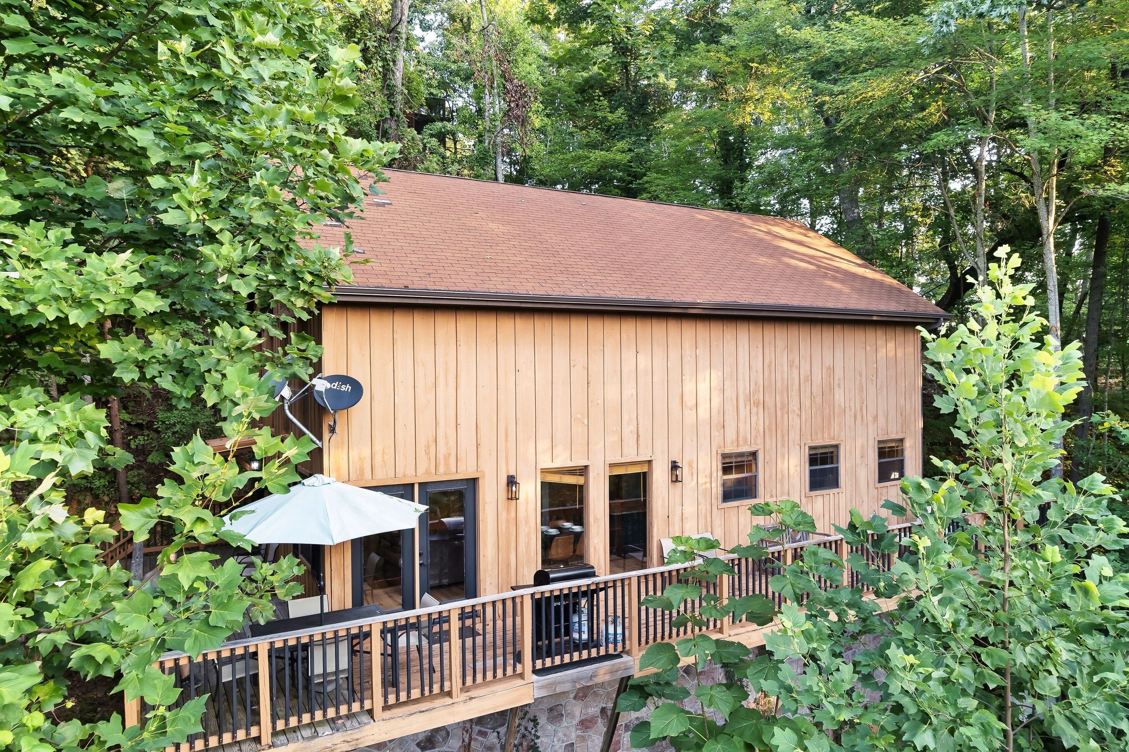 A wooden cabin with a balcony, surrounded by trees.