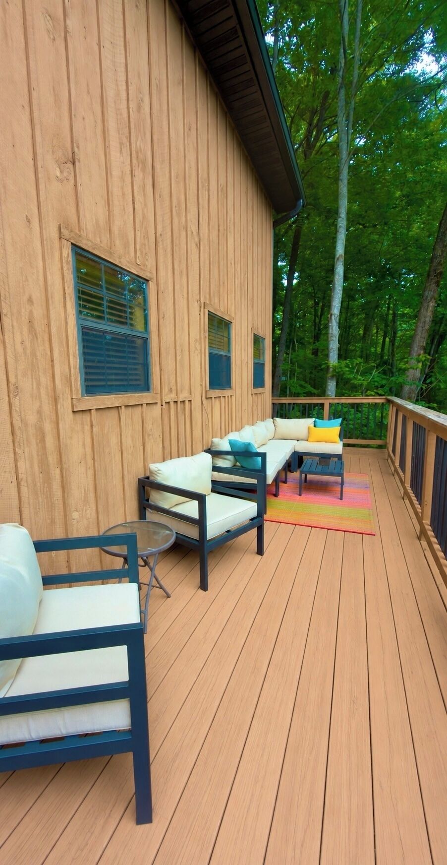 A wooden deck with outdoor furniture, including a sofa and chairs, and a small table.