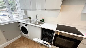 A compact kitchen with a built-in washing machine, a dishwasher, and an oven. - Heart of London Bridge - Central (London)