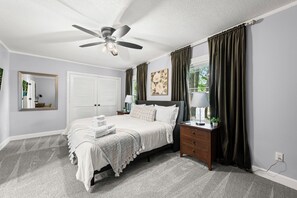 Ein Schlafzimmer mit Bett, Nachttisch, Lampe und Vorhängen.