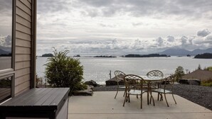 En terrasse med bord og stole med udsigt over vand og fjerne øer.