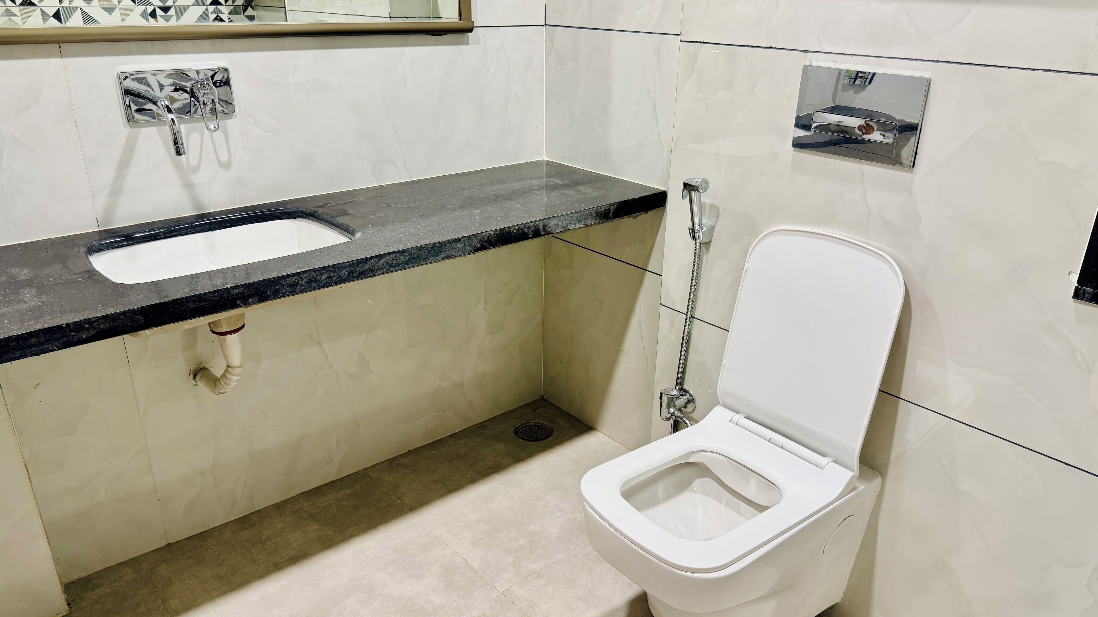 Une petite salle de bain avec des toilettes blanches, un lavabo doté d’un plan-vasque noir et un espace douche.
