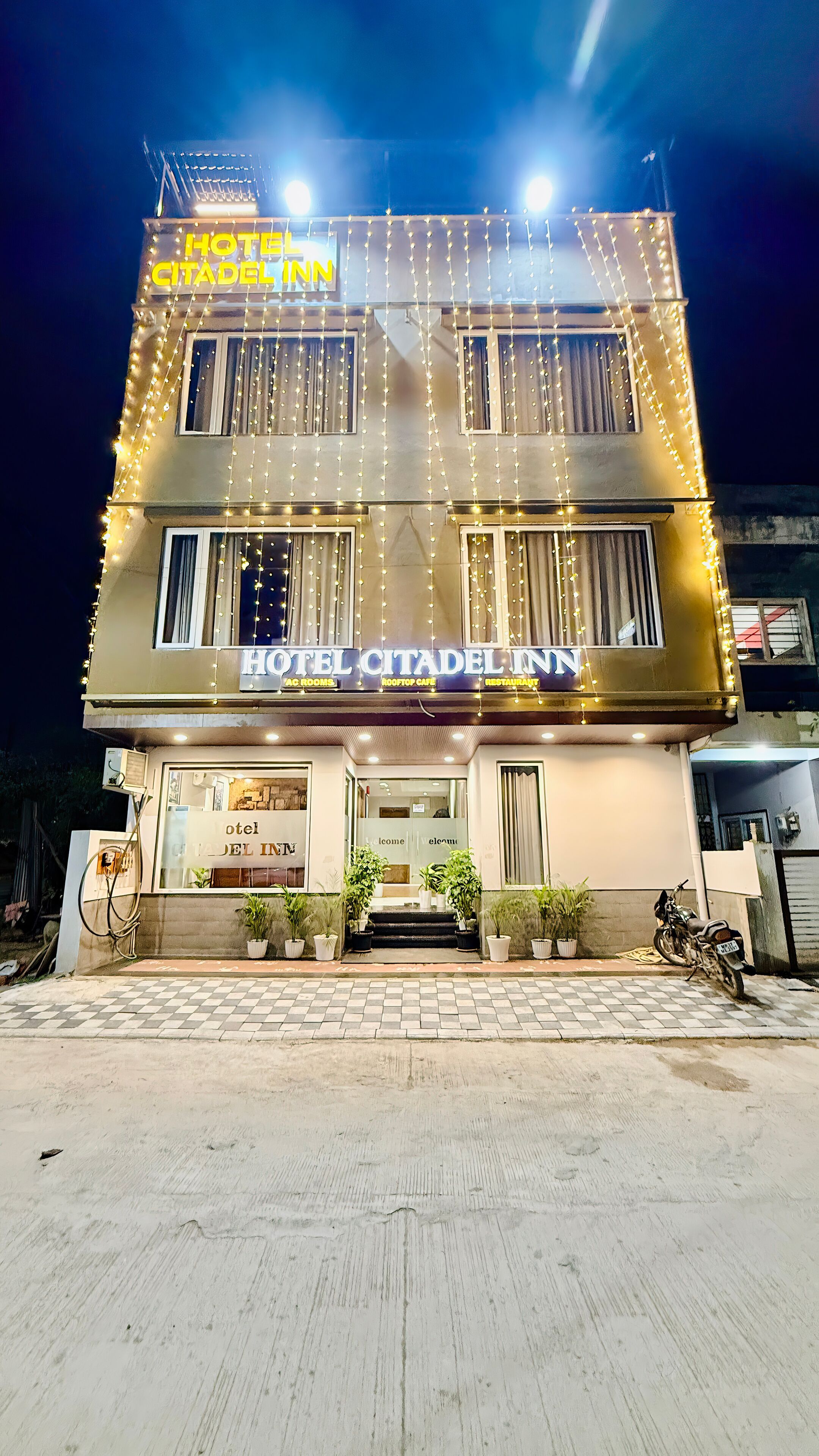 A hotel named "HOTEL CITADEL INN" with a signboard indicating "AC ROOMS," "ROOFTOP CAFE," and "RESTAURANT."