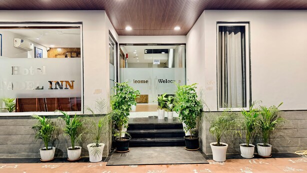 L’entrée d’un hôtel, avec un comptoir d’accueil, une pancarte « Bienvenue » et des plantes en pot.