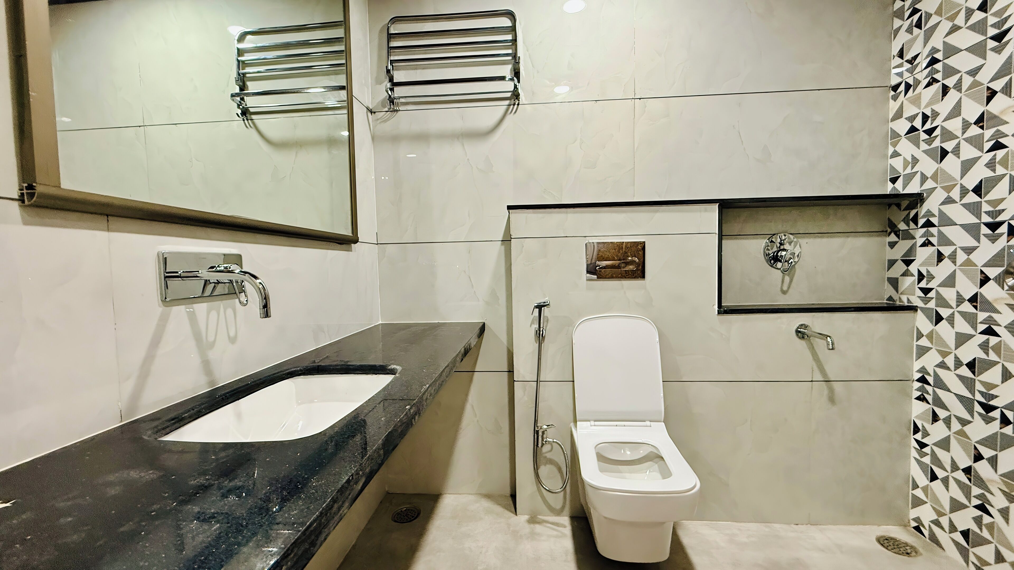 A bathroom with a black marble sink, a white toilet, a mirror, and a shower.