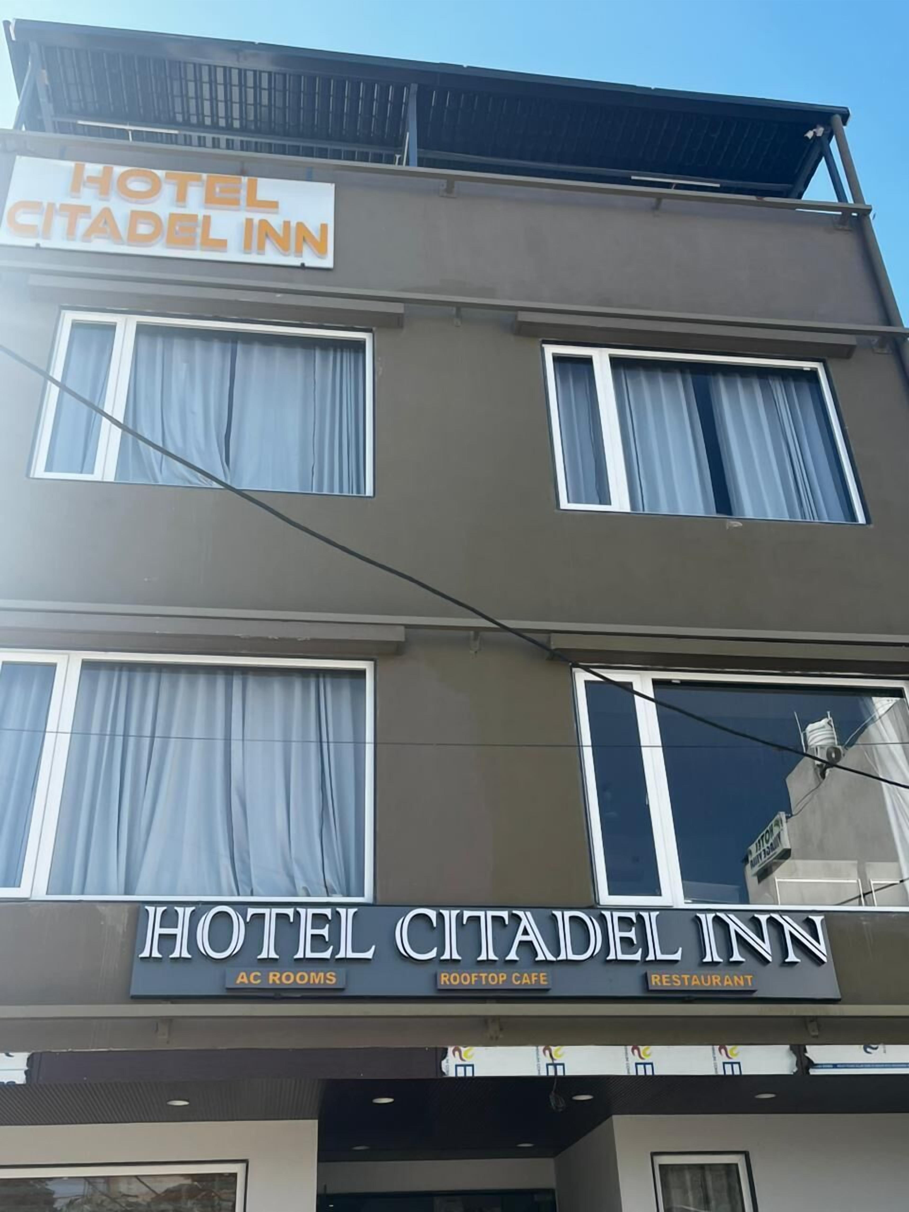 A multi-story building with a sign reading "HOTEL CITADEL INN" and "AC ROOMS" below.