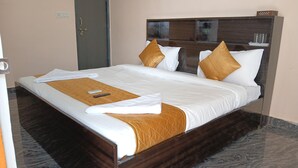 A neatly made bed with white linens, a brown throw blanket, and two gold pillows. - HOTEL PRICELESS AMITY UNIVERSITY LUCKNOW (Lucknow)