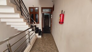 A hallway with a marble floor, a staircase with metal railings, and a fire extinguisher mounted on the wall. - HOTEL PRICELESS AMITY UNIVERSITY LUCKNOW (Lucknow)