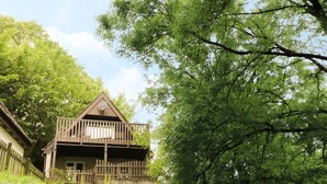 A wooden cabin with a balcony, surrounded by lush greenery and trees. - Valley Lodge 61 (Gunnislake)