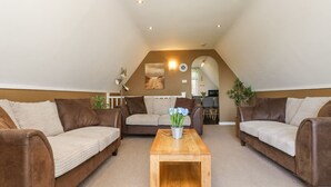 A cozy loft-style living room with two brown sofas, a wooden coffee table, and a dining area in the background. - Valley Lodge 61 (Gunnislake)
