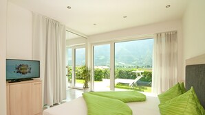 Een moderne hotelkamer met een groot bed, een televisie en een balkon met uitzicht op het landschap.
