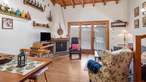 Una sala de estar acogedora con techo de madera, chimenea, televisor y comedor con mesa y sillas.